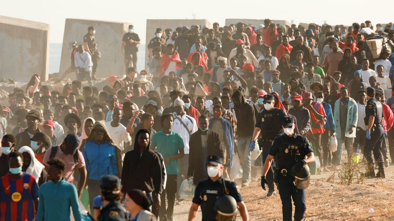 Agents de la Policia Nacional conduixen migrants de Ceuta cap a un allotjament provisional després de l'entrada massiva de finals de juliol