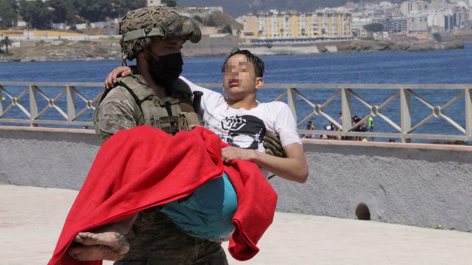 Un soldat espanyol trasllada un menor en la platja fronterera del Tarajal de Ceuta