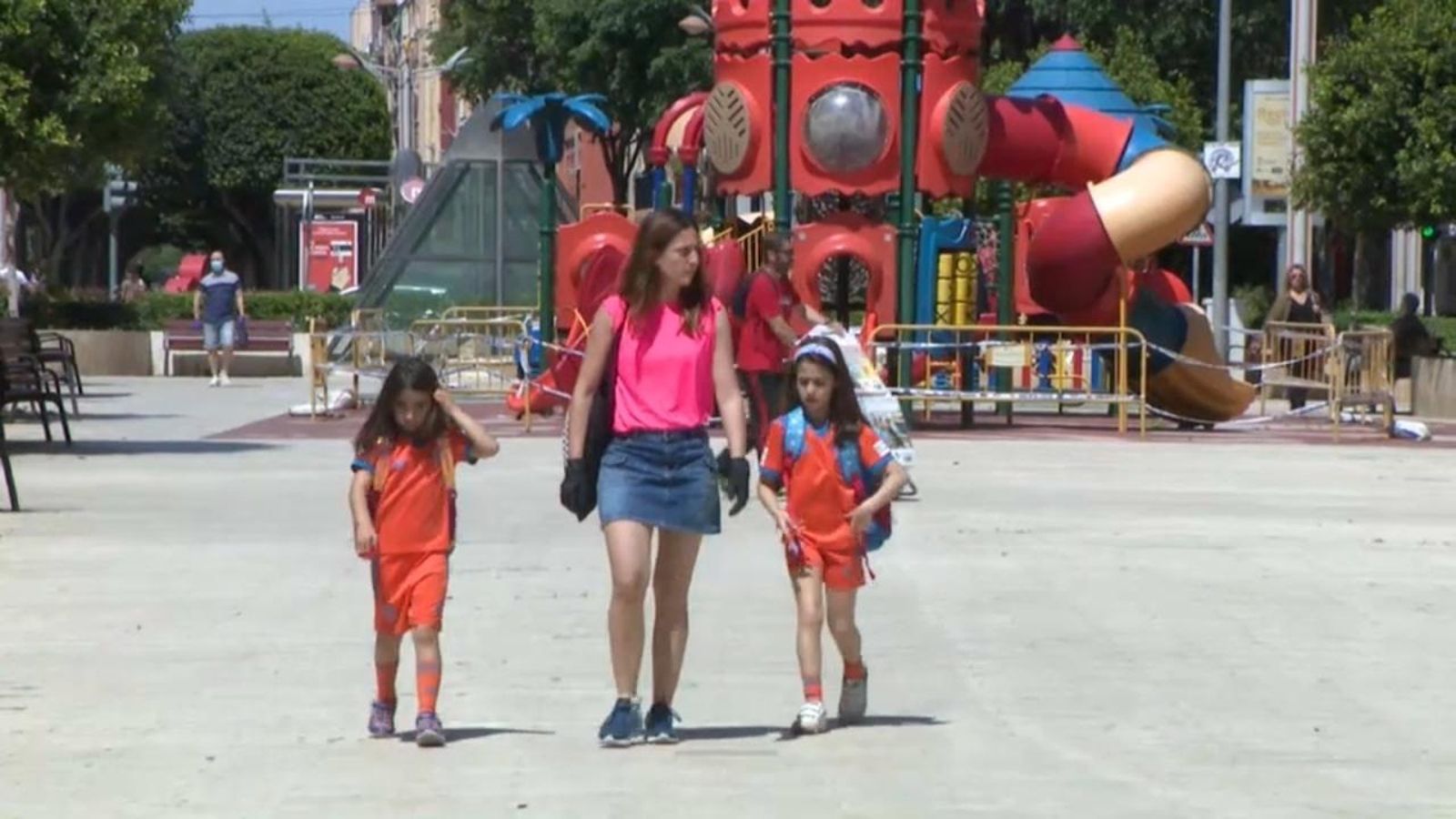 Una dona amb dues xiquetes passeja per un parc