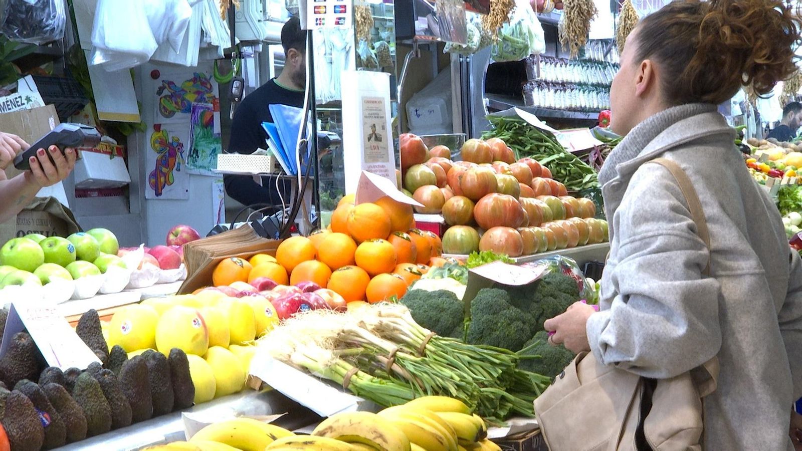 Una dona en l'aparador de fruites i verdures d'un mercat Una dona en l'aparador de fruites i verdures d'un mercat