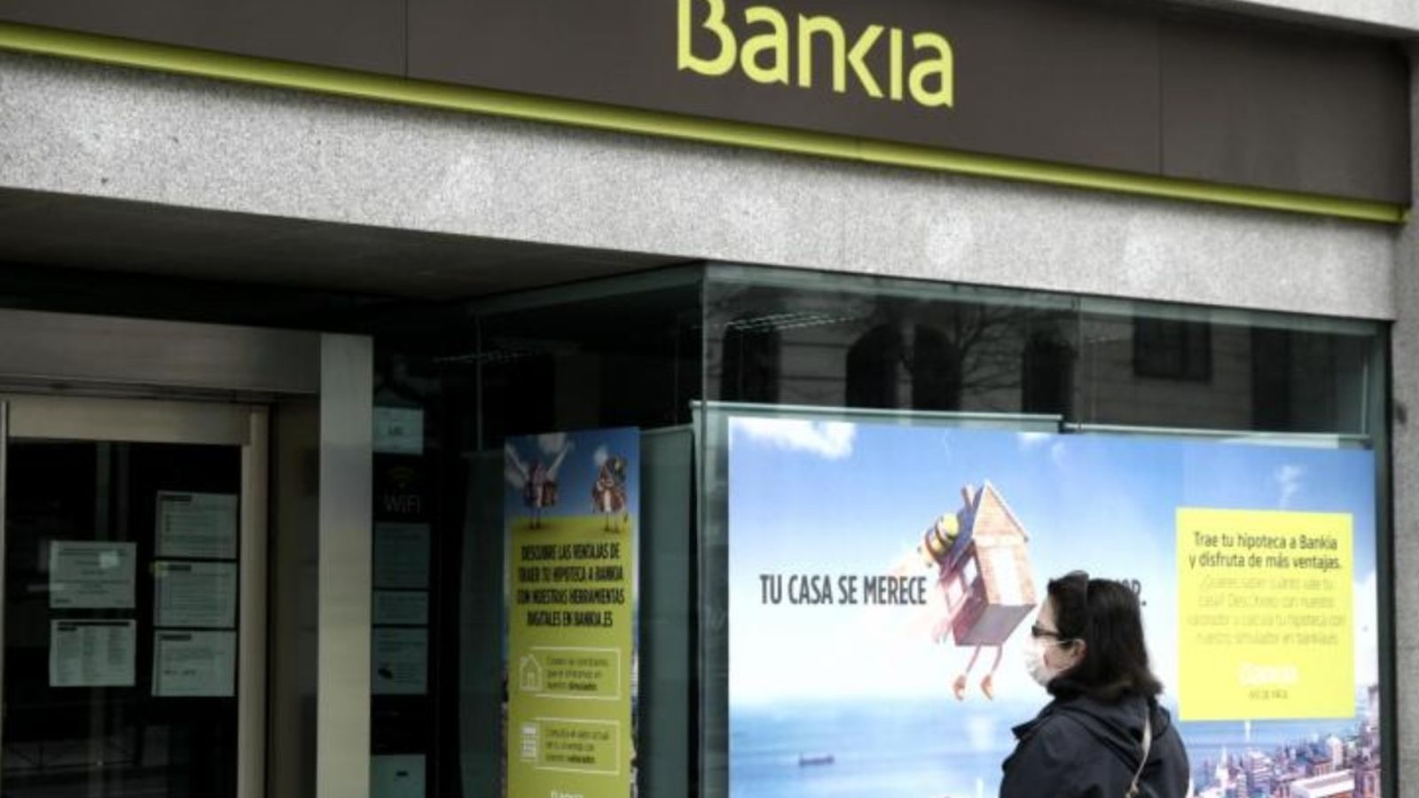 Imatge d'arxiu d'una dona davant d'una oficina bancària