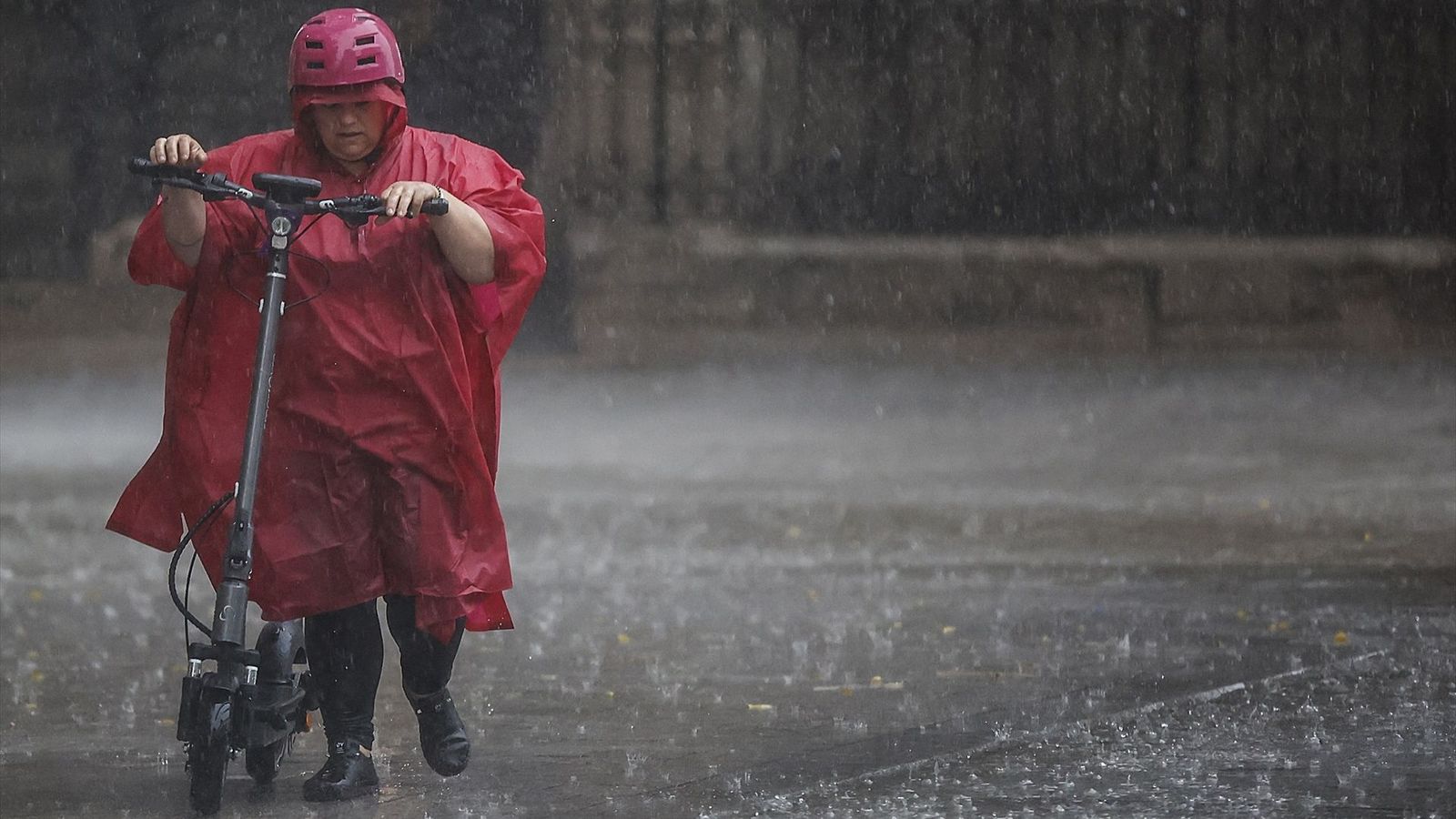 Una dona circula en un patinet enmig de la pluja (arxiu)