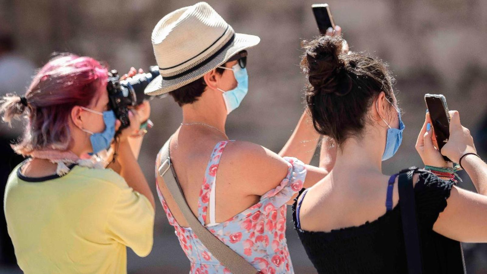 Tres turistes fan una foto mentre recorren la ciutat de València, inusualment buida de turistes aquest agost, a causa de la crisi sanitària