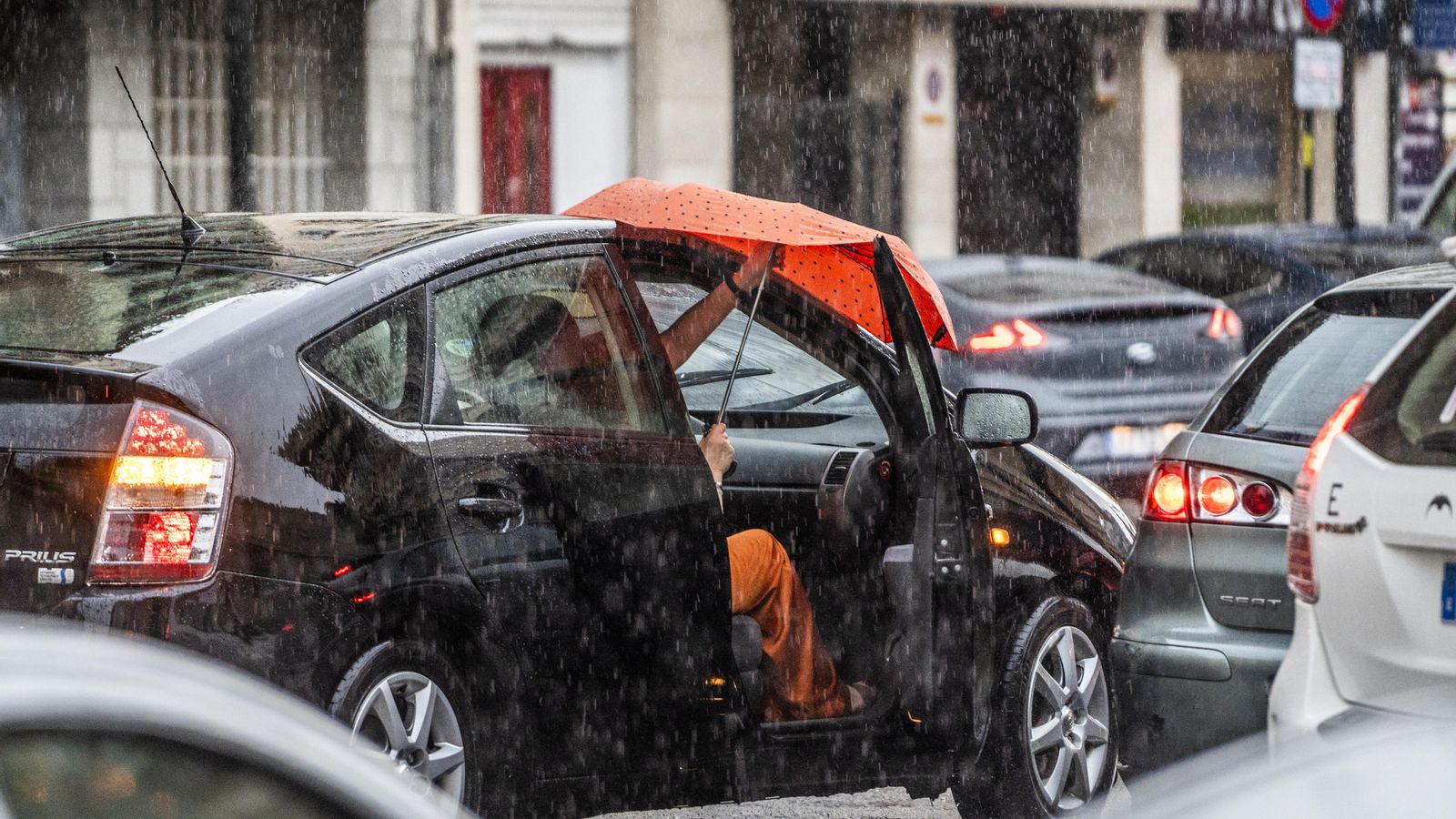 Un home puja al vehicle enmig de la plutja