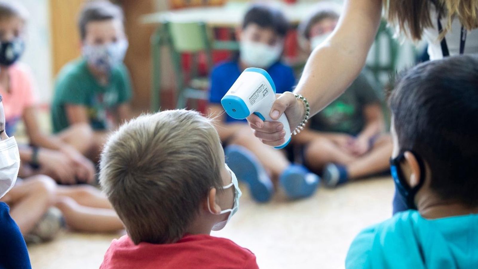 Una docent pren la temperatura a un alumne en una imatge d'arxiu