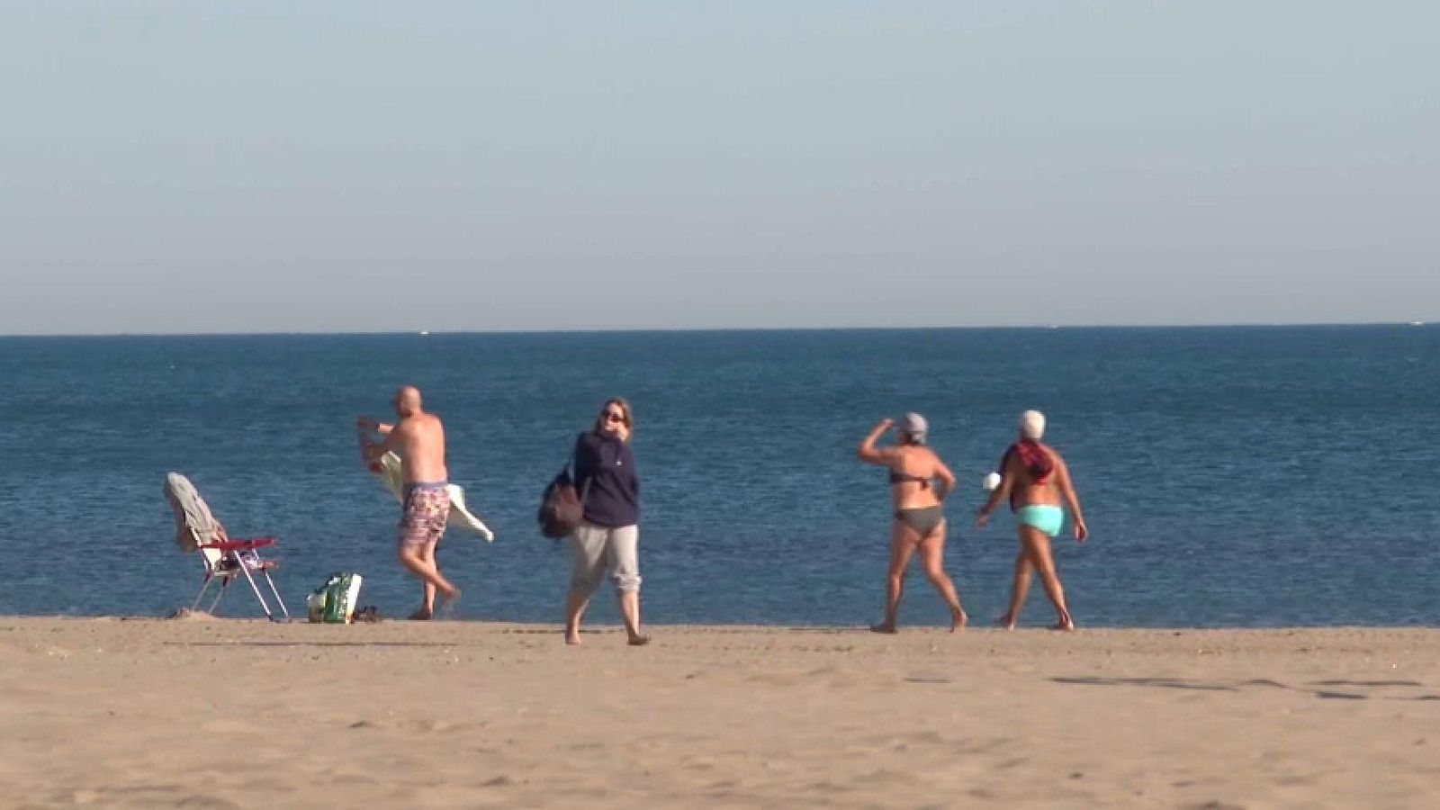 Diverses persones passegen per la platja de la Patacona, a Alboraia, aquest divendres, en ple desembre, quan s'espera assolir els 25 graus al litoral