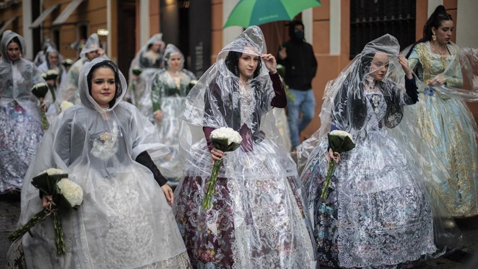 Unes falleres es protegeixen de la pluja amb impermeables durant l'Ofrena Unes falleres es protegeixen de la pluja amb impermeables durant l'Ofrena