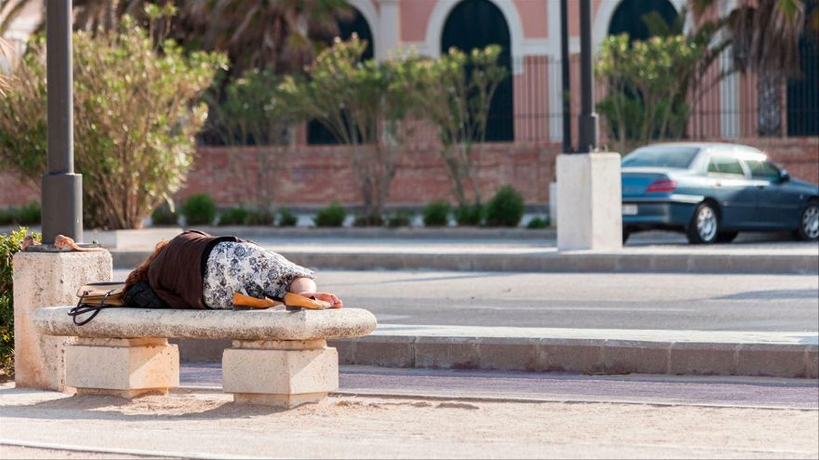 Una persona sense sostre dorm a un banc a València