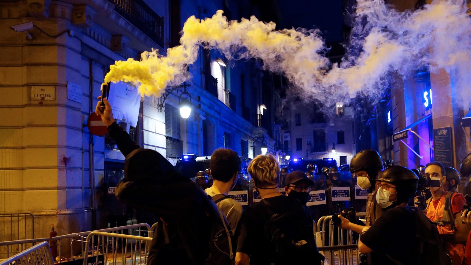Un manifestant amb una bengala encesa davant dels Mossos d'Esquadra durant els altercats
