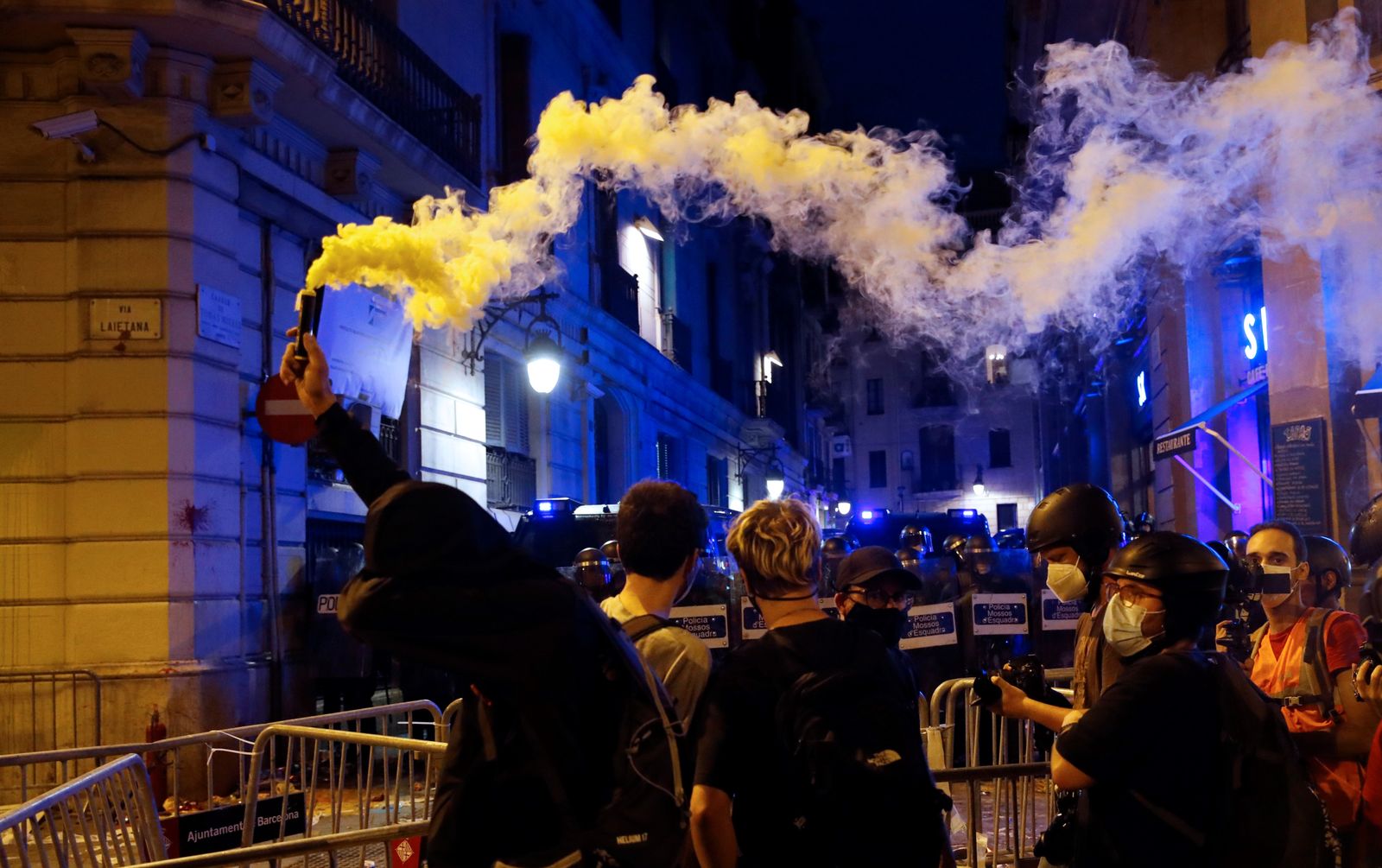 Un manifestant amb una bengala encesa davant dels Mossos d'Esquadra durant els altercats