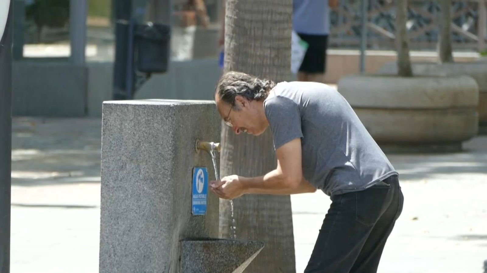 Un home es refresca de la calor en una font