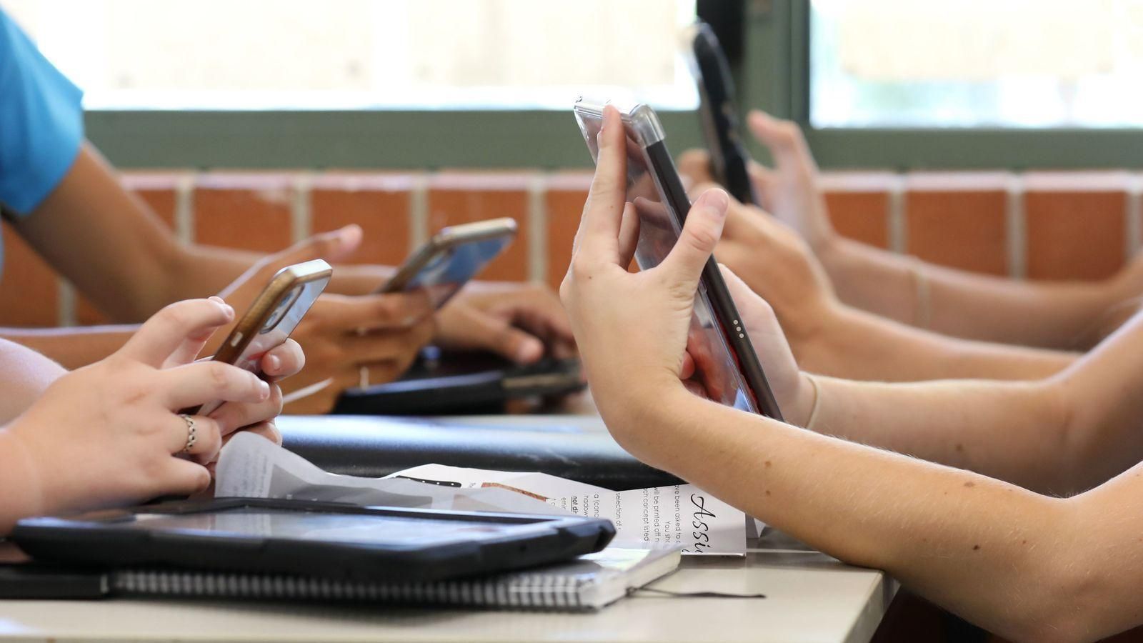 Imatge d'arxiu d'uns adolescents amb el telèfon a classe Imatge d'arxiu d'uns adolescents amb el telèfon a classe