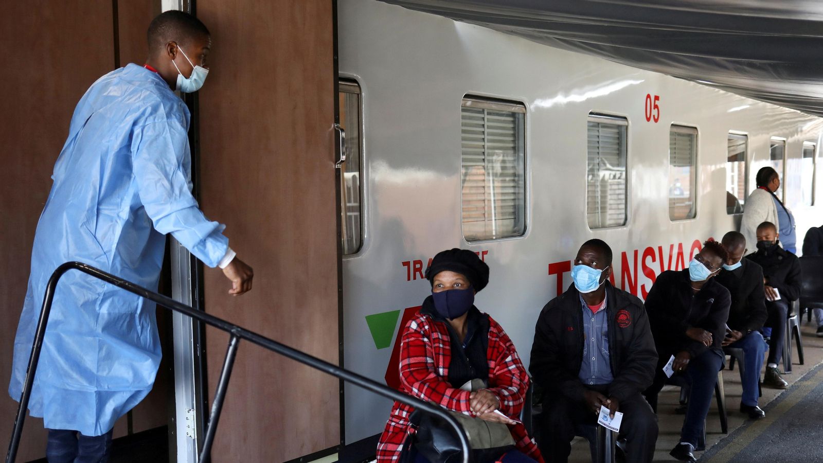Diverses persones esperen per a entrar en un dels trens de la companyia Transnet que s'ha habilitat com a centre de vacunació contra la Covid-19