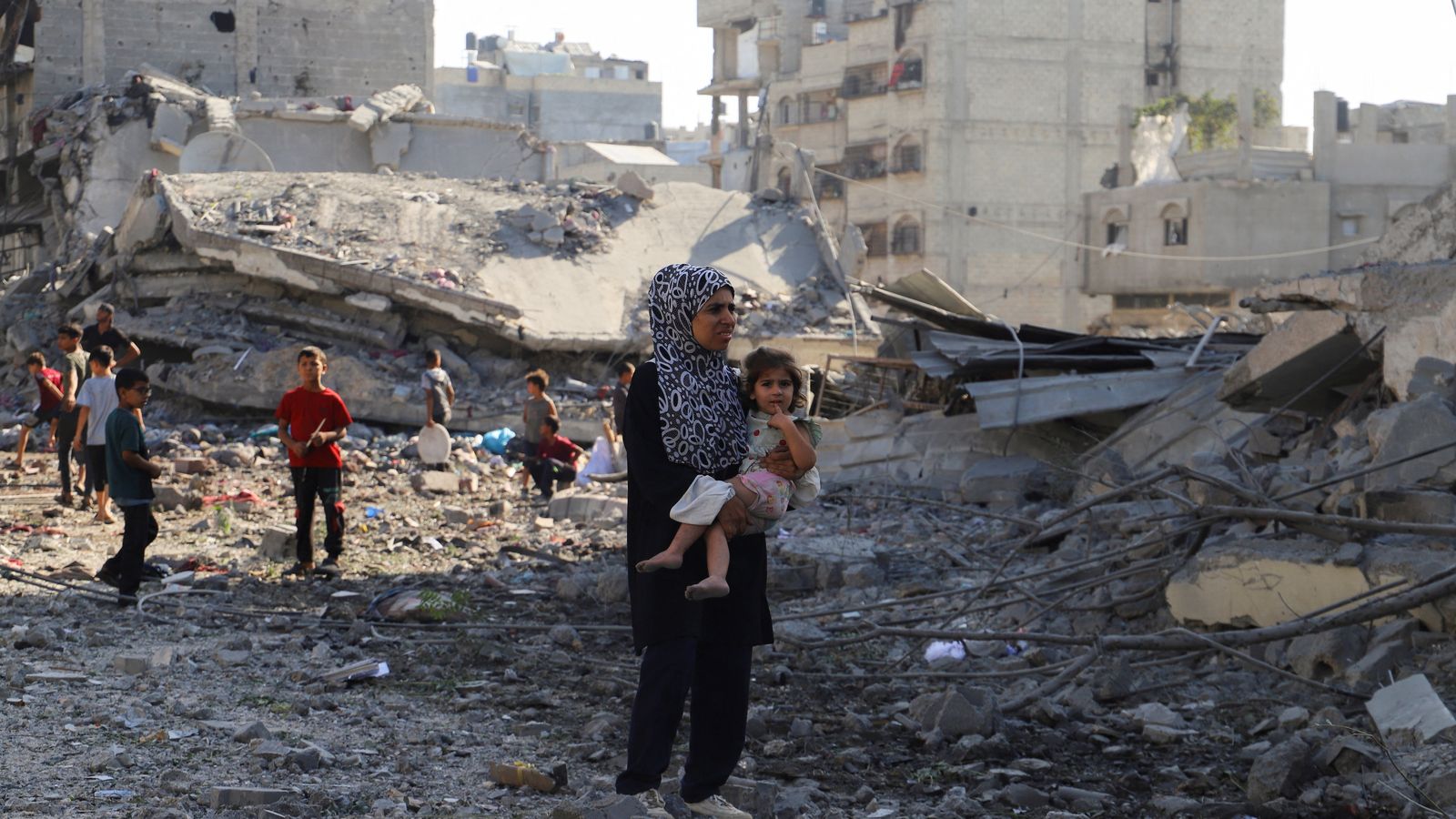 Una dona palestina porta el seu fill, mentre deambulen a la ciutat de Gaza