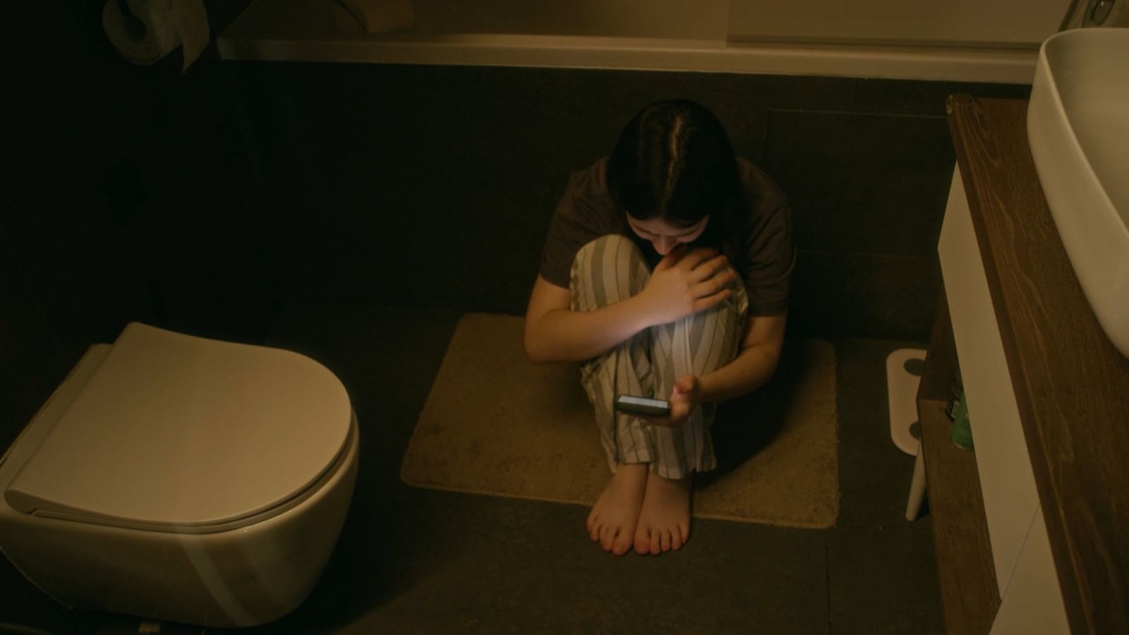 Una xiqueta sola es refugia en el telèfon