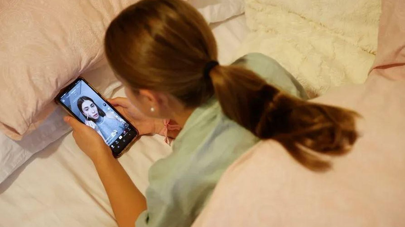 Una adolescent mira vídeos en una plataforma a través del telèfon Una adolescent mira vídeos a una plataforma a través del seu telèfon