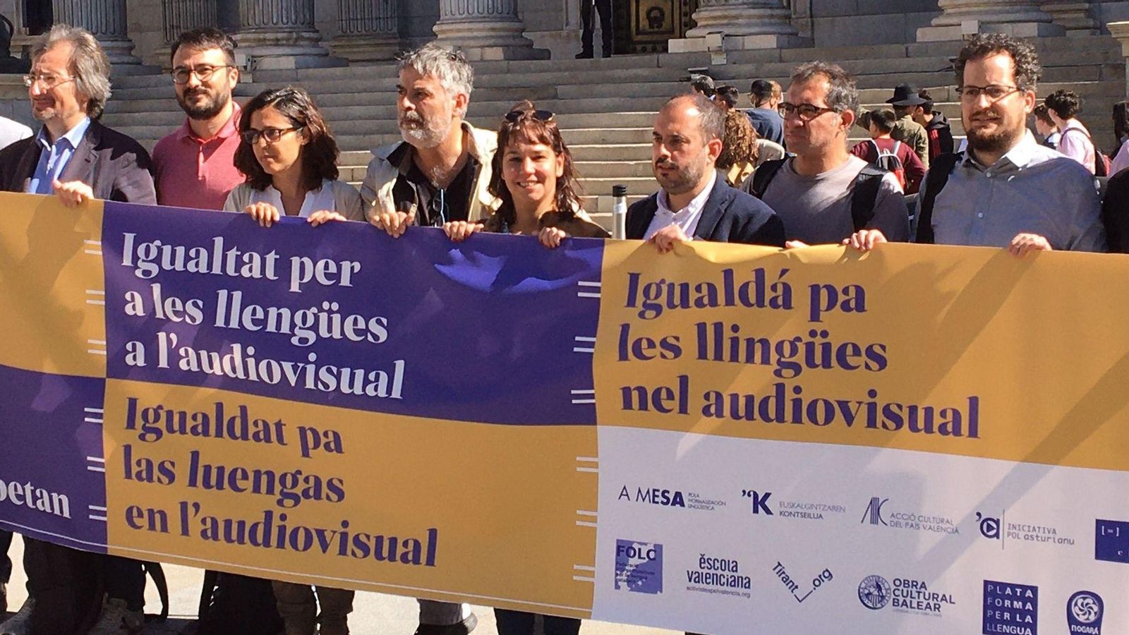Representants en defensa del gallec, el basc, el valencià i l'asturià amb la pancarta que han desplegat a les portes del Congrés