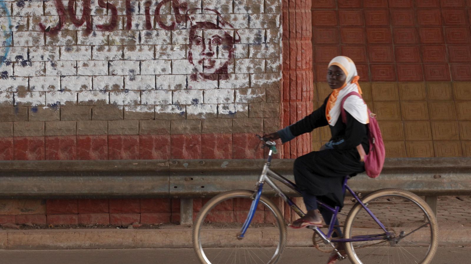 Una dona passa amb bicicleta per davant d'un grafitti que demana justícia
