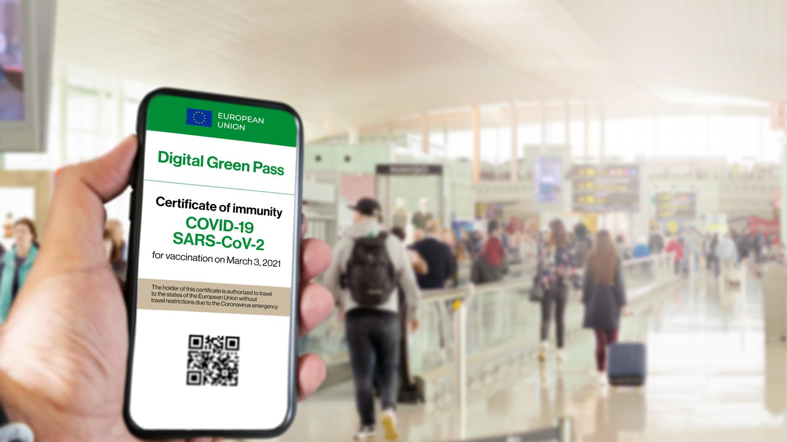 El certificat verd digital de la unió europea amb el codi QR en la pantalla d'un mòbil amb una mà amb un aeroport borrós en el fons. Immunitat de Covid-19. Viatjar sense restriccions.