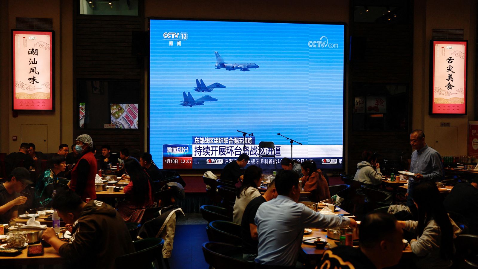 Una pantalla informa de les maniobres militars xineses a la clientela d'un restaurant de Pequín Una pantalla informa de les maniobres militars xineses a la clientela d'un restaurant de Pequín