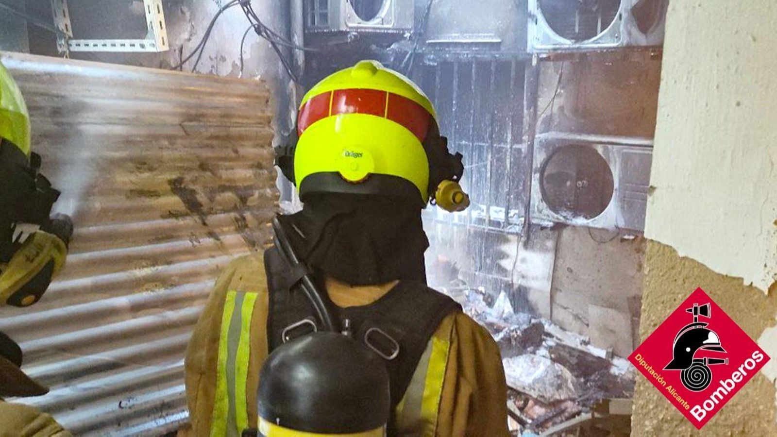 Dos dels bombers que van intervindre passen per davant dels nombrosos aparells d'aire condicionat instal·lats a les vivendes per a mantindre les plantacions de marihuana