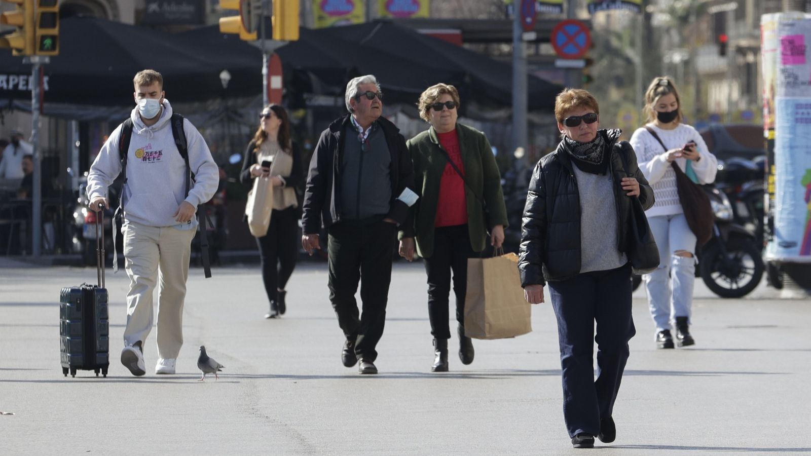 Diversos vianants passegen pel centre d'una gran ciutat sense mascareta, després que haja decaigut aquesta obligació