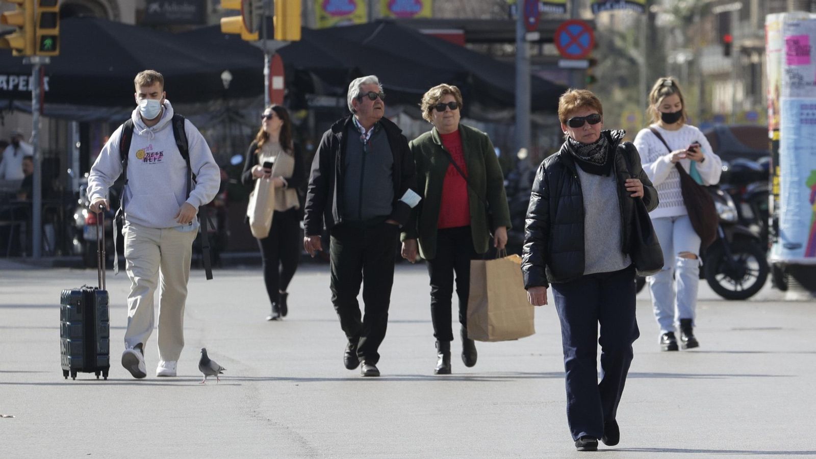 Diversos vianants passegen pel centre d'una gran ciutat sense mascareta, després que s'haja eliminat aquesta obligació Diversos vianants passegen pel centre d'una gran ciutat sense mascareta, després que haja decaigut aquesta obligació