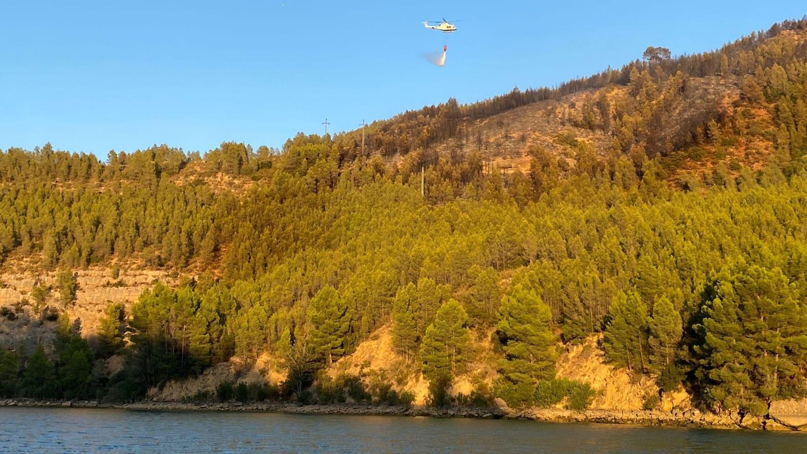 Un mitjà aeri realitza una descàrrega d'aigua a la zona de l'incendi