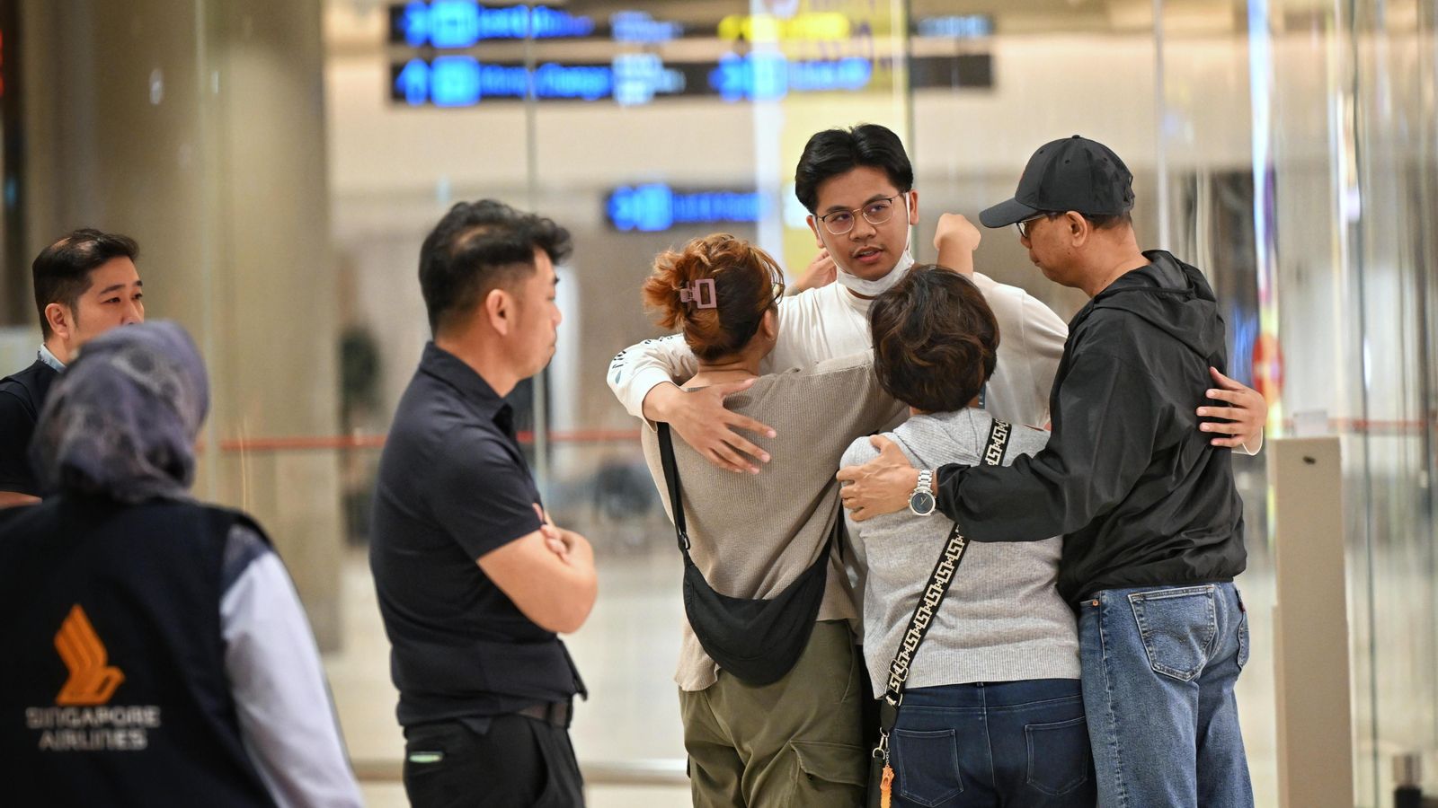Els passatgers del vol SQ321 de Singapore Airlines, que va aterrar d'emergència a Bangkok, saluden als seus familiars a l'arribada a l'aeroport de Changi a Singapur