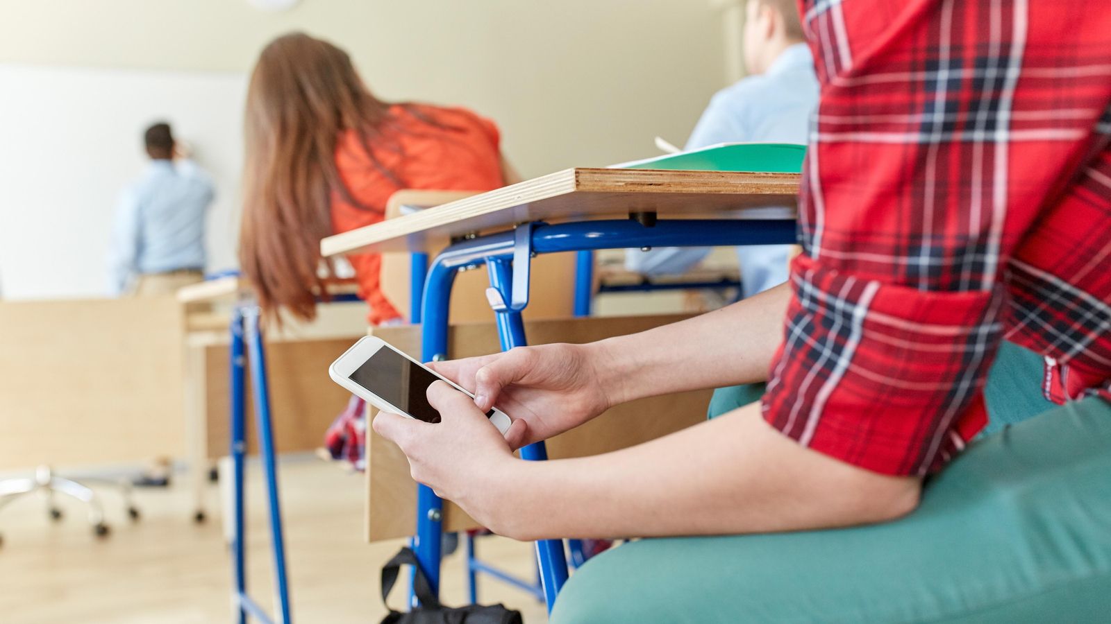 Un alumne consulta el mòbil durant una classe