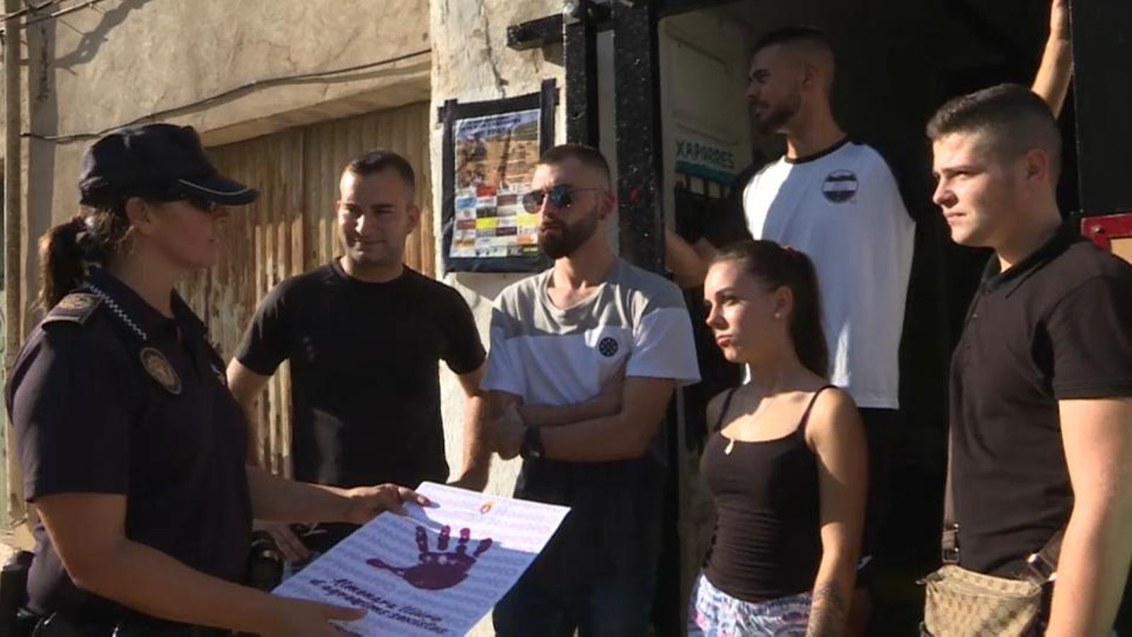 Una agent de la Policia Local entrega els cartells de la campanya als joves