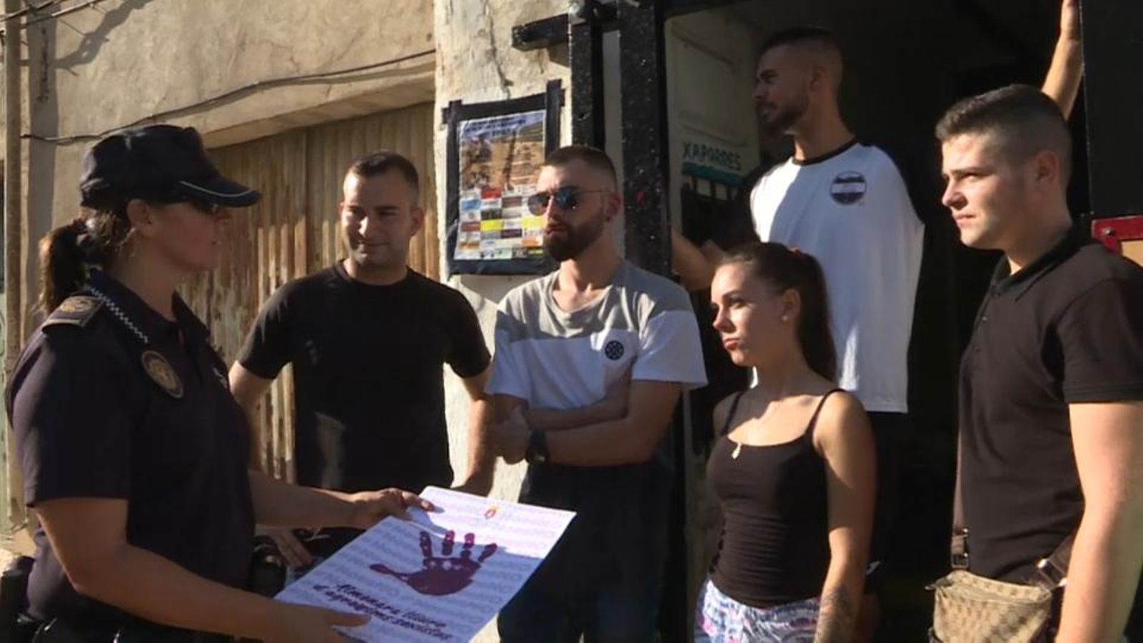 Una agent de la Policia Local entrega els cartells de la campanya als joves