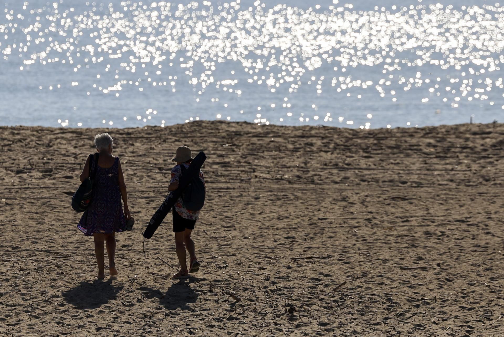 Dos persones caminen per una platja de València Dos persones caminen per una platja de València