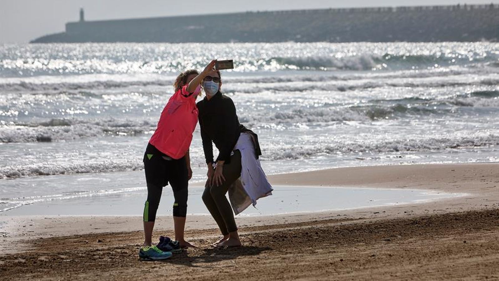 Dues turistes es fan una foto a la platja de Gandia