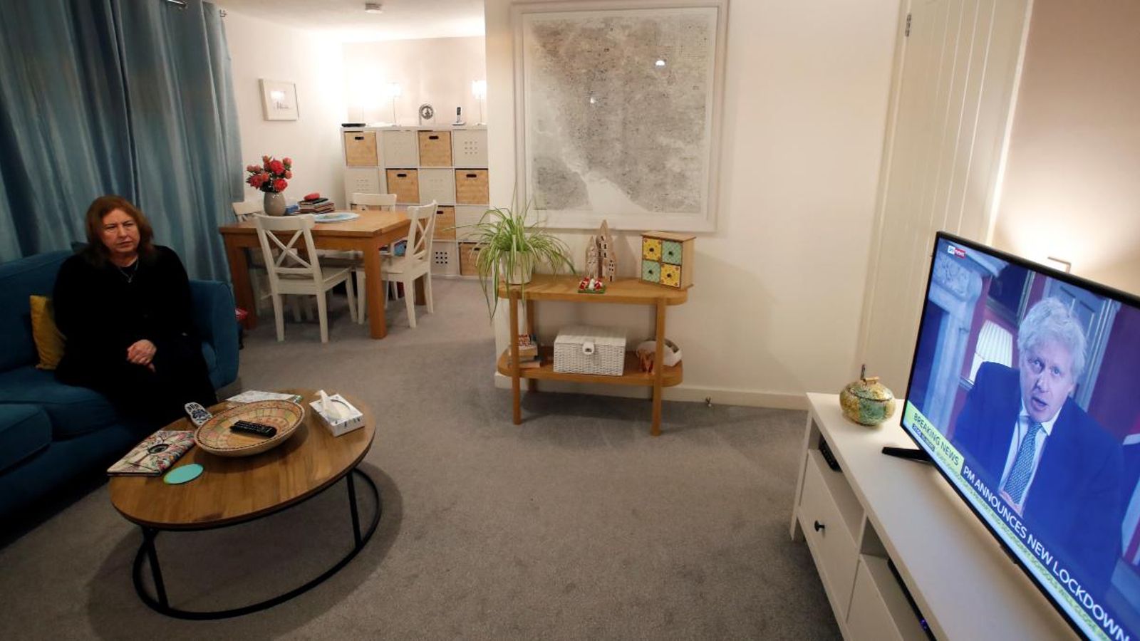 Una dona veu el discurs de Boris Johnson en la televisió