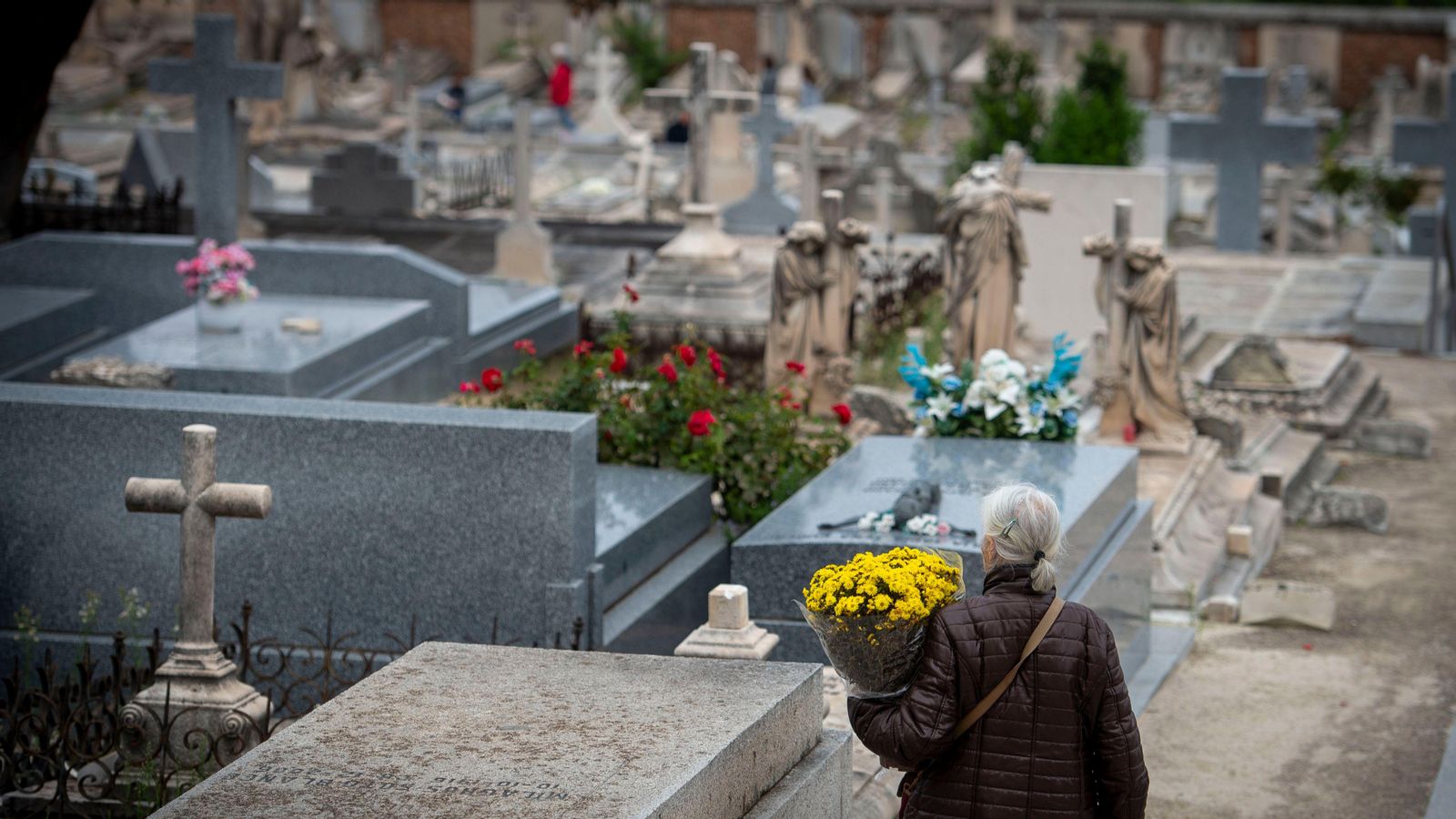 Una dona porta flors al cementeri, en una imatge d'arxiu