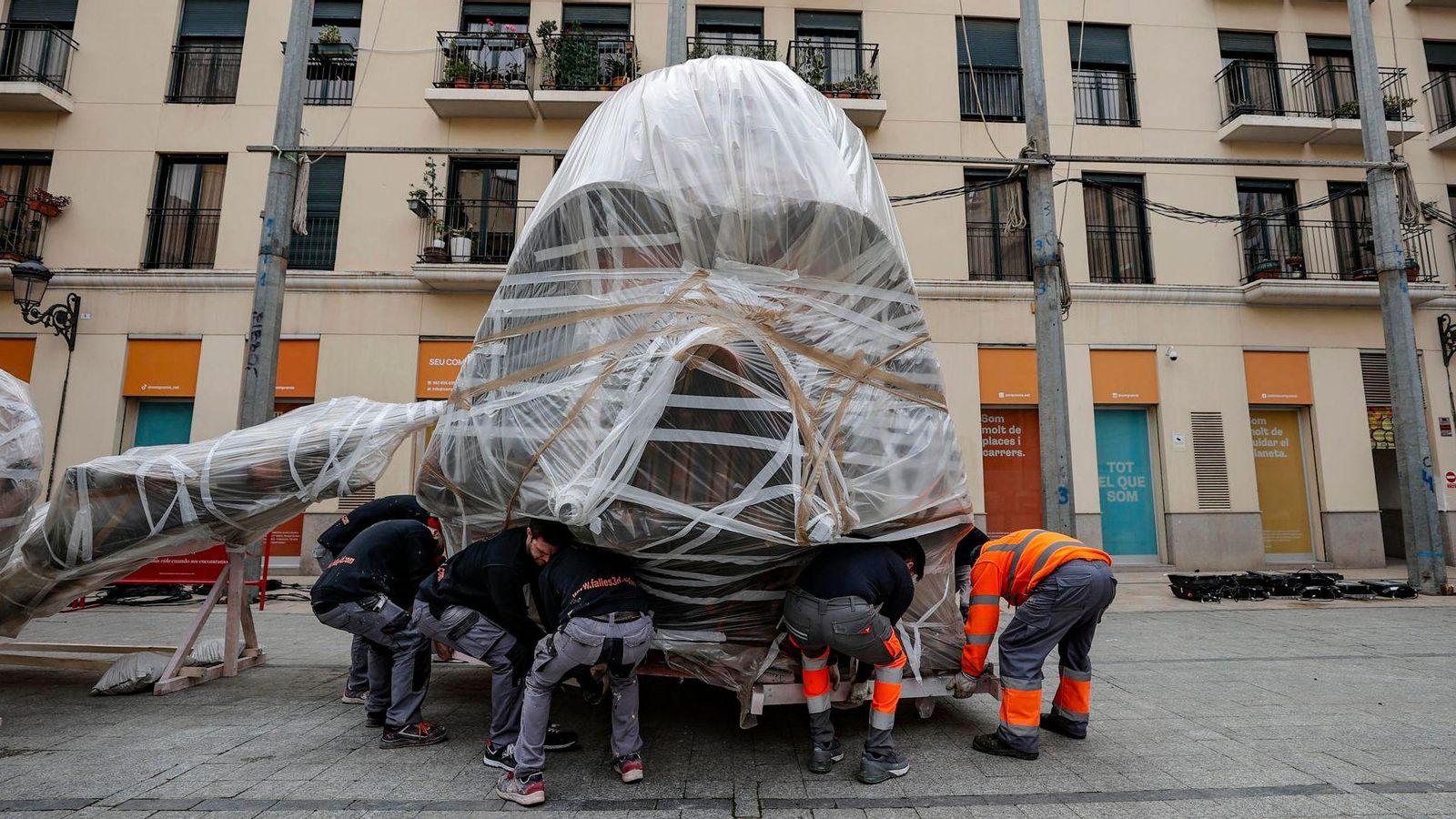 Membres d'un taller faller traslladen una de les peces del monument de la falla Plaça del Pilar, a València