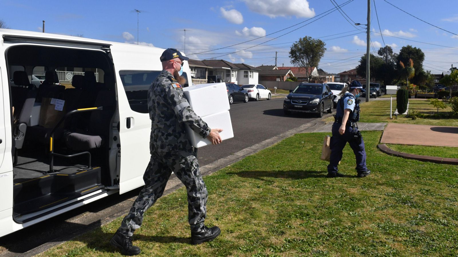 Un soldat trasllada unes caixes, junt a una agent de policia, pels carrers de la regió de Sidney