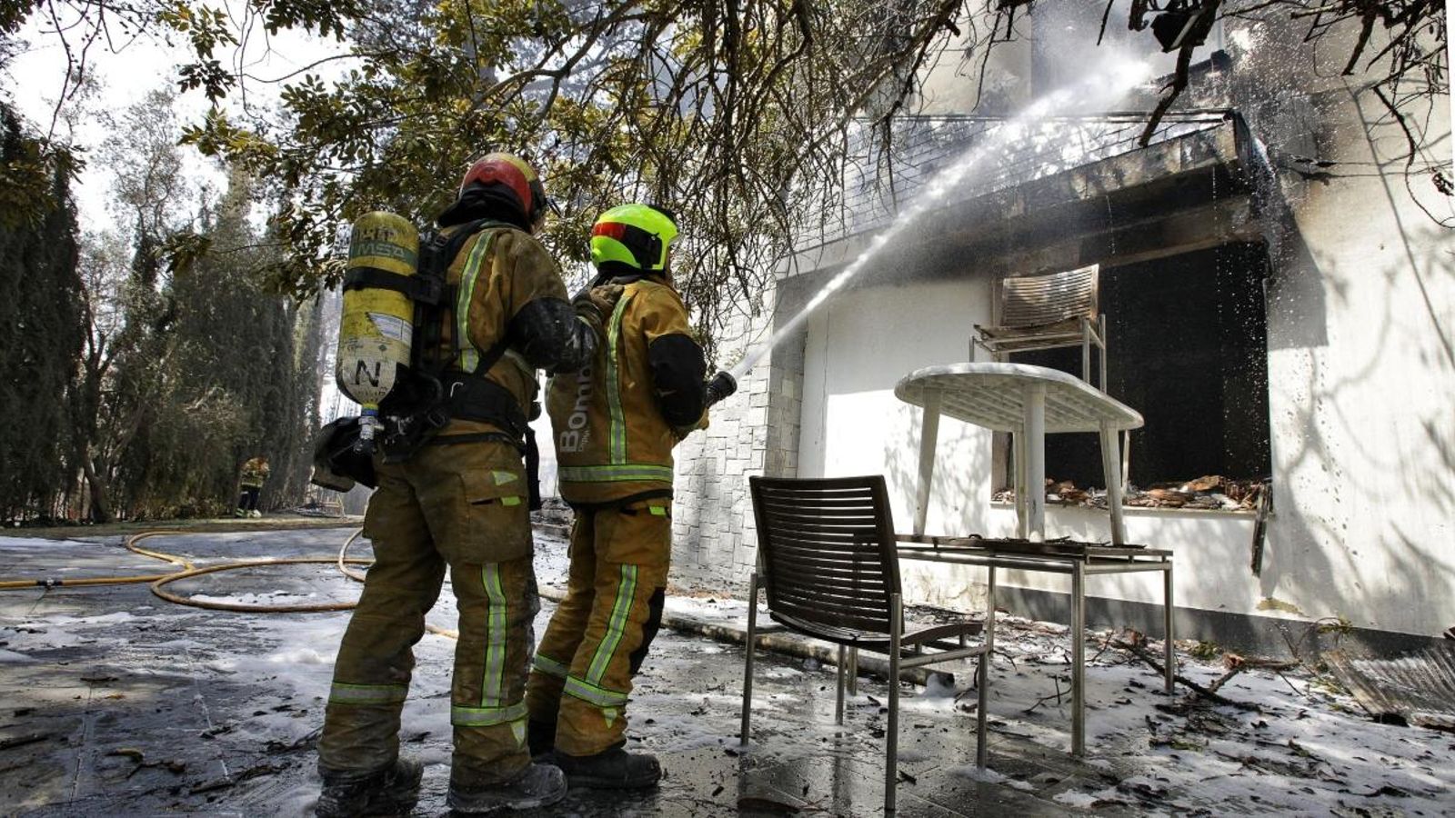 Dos bombers refreden l'interior d'una de les vivendes afectades per l'incendi de Llutxent