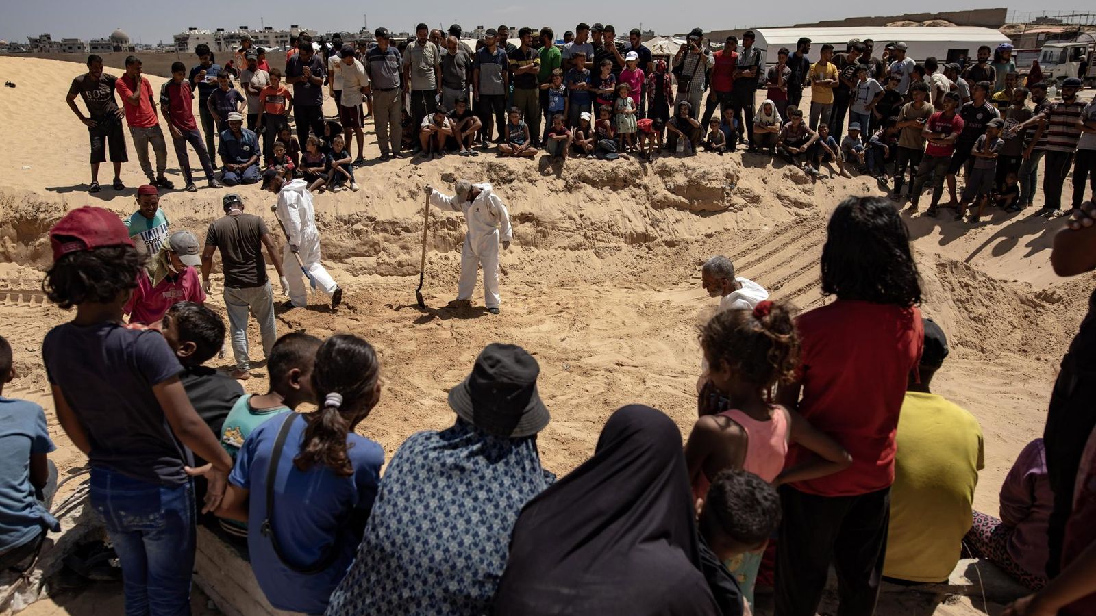 Desenes de gazians observen l'excavació de la tomba on soterraran els 84 morts del bombardeig israelià/ EFE