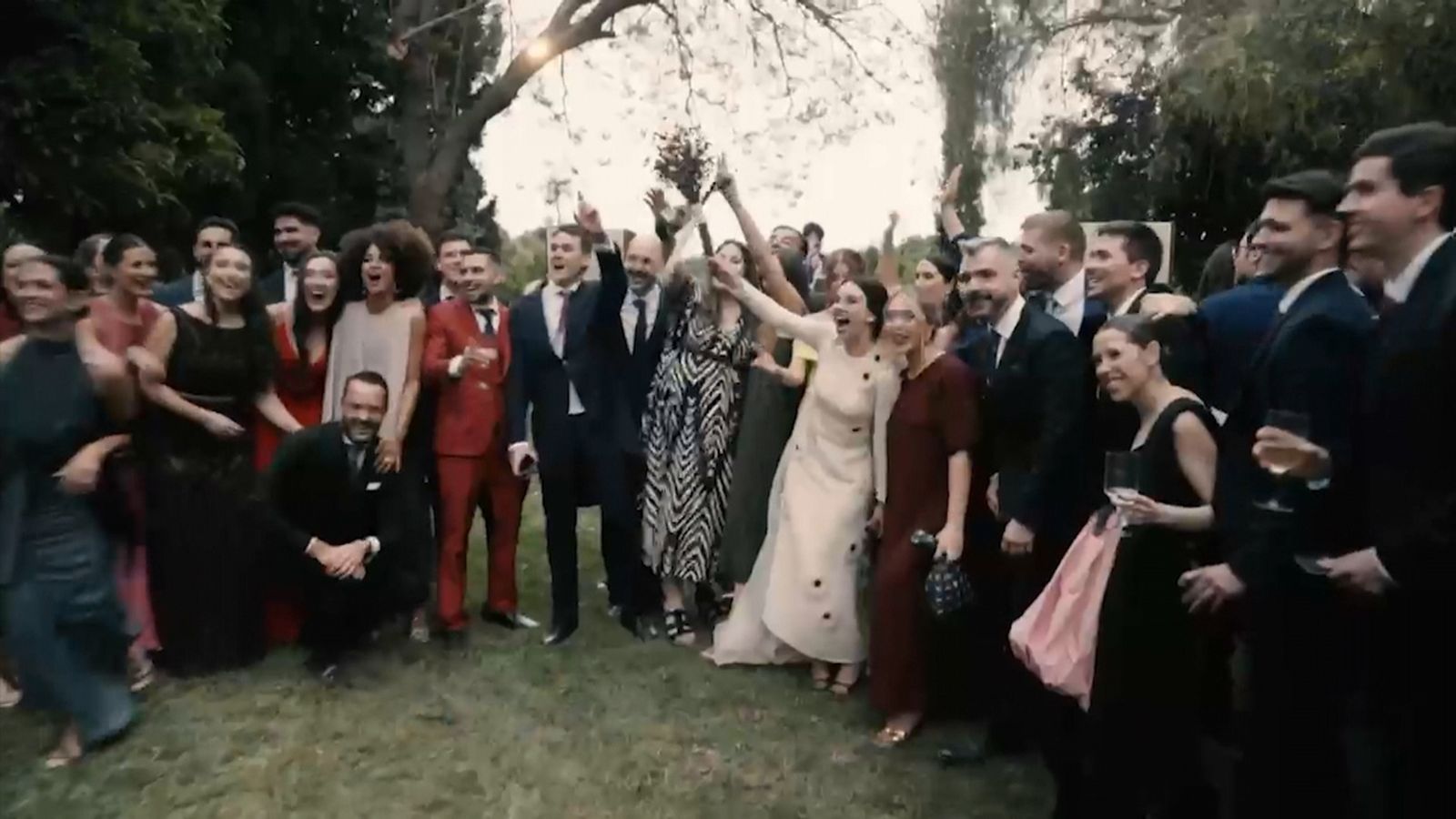 Un grup d'amics i amigues celebra el casament d'una parella en un jardí