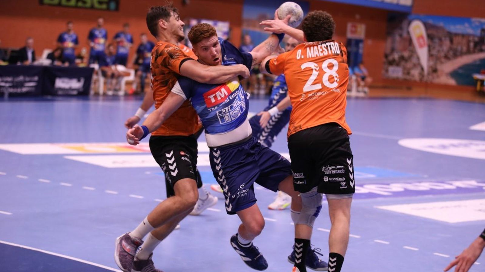 Un jugador del Benidorm fa un llançament entre dos jugadors del Torrelavega