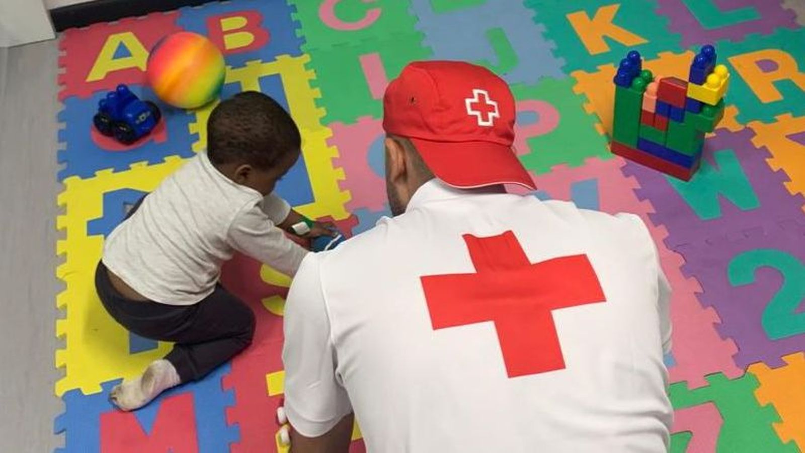 La xiqueta de bolquers rescatada de la pastera juga amb un voluntari de la Creu Roja