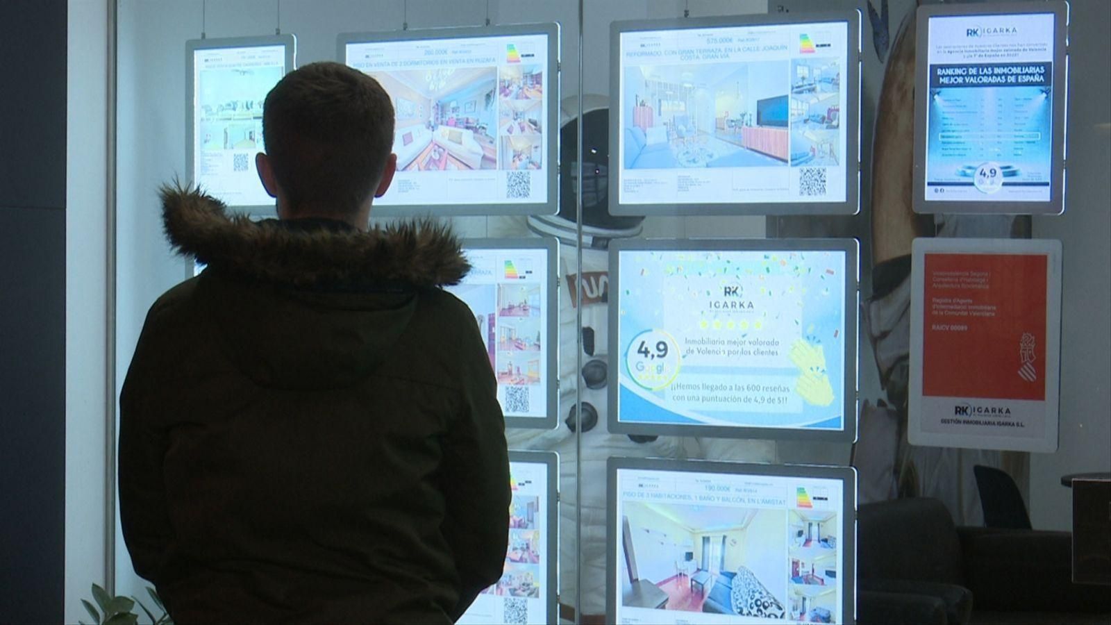 Un jove mira un aparador d'una immobiliària