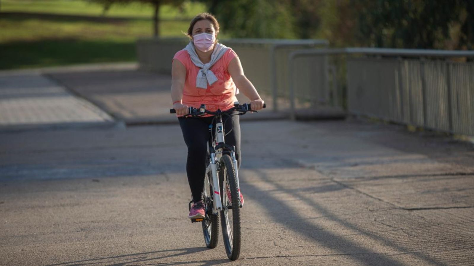 Una dona usa mascareta mentre va en bicicleta