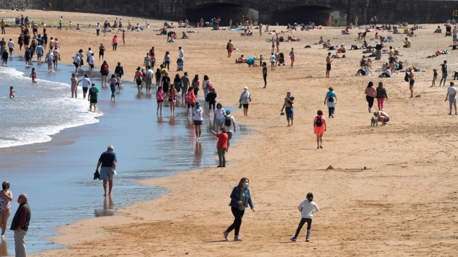 Diverses persones gaudeixen del bon temps a la platja de Sant Lorenzo, aquest dissabte a Gijón