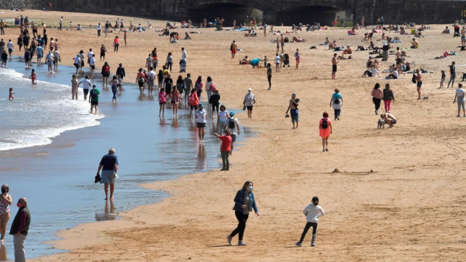 Diverses persones gaudeixen del bon temps a la platja de Sant Lorenzo, aquest dissabte a Gijón