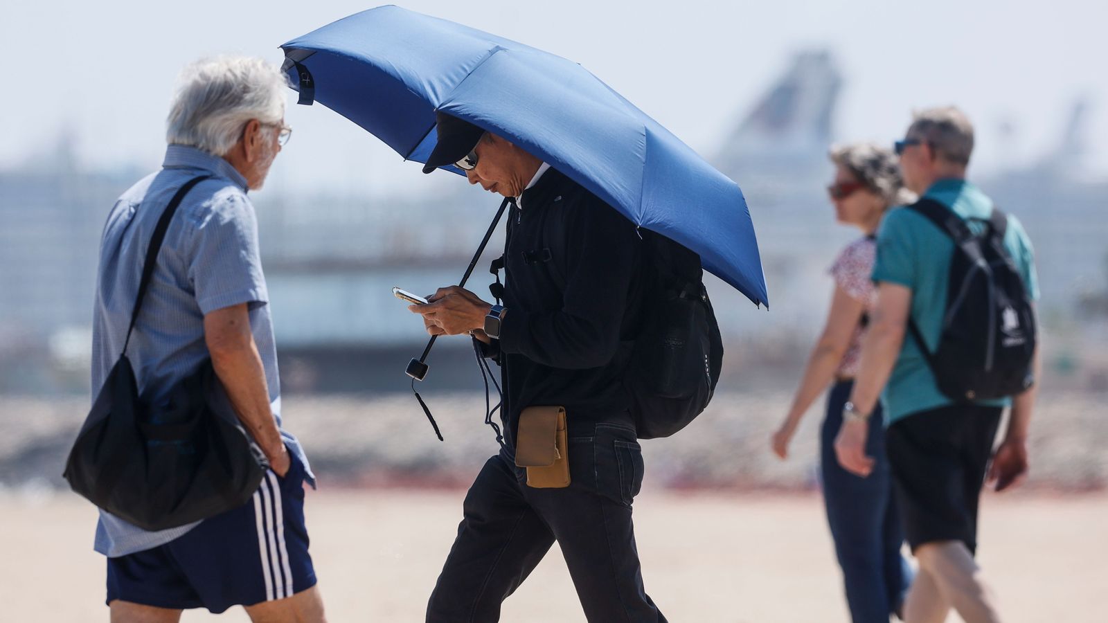 Un turista es protegeix amb un paraigua del sol en la zona de la Malvarrosa de València