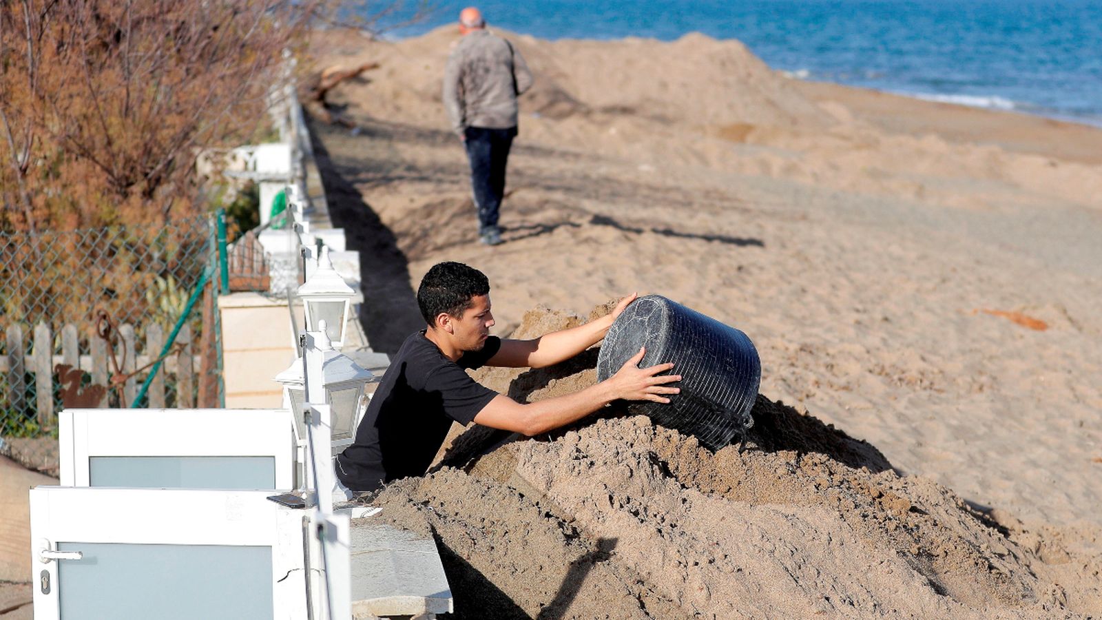 Un home retira els vora dos metres d’arena que el temporal Gloria ha acumulat davant la seua vivenda a Dénia