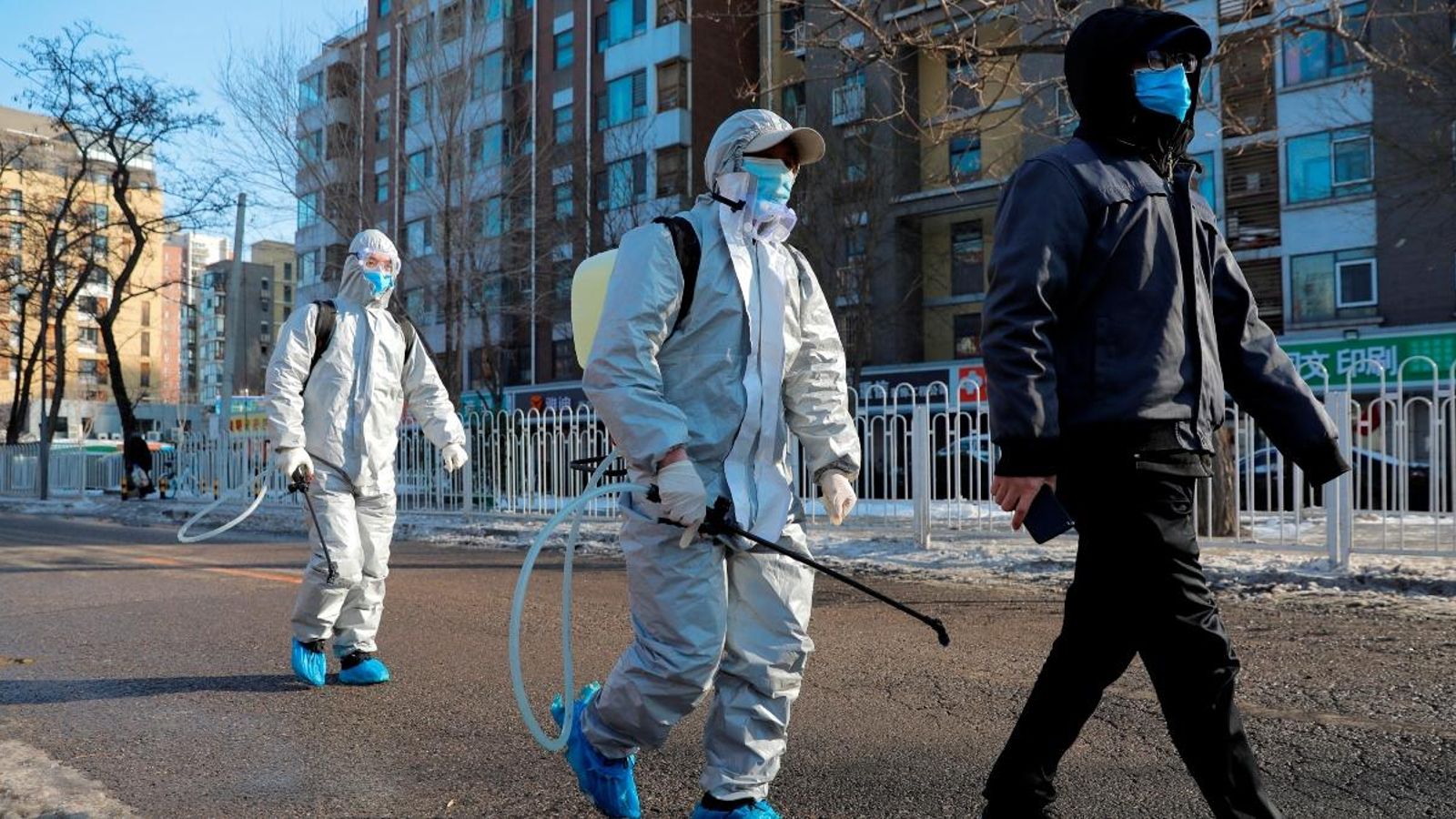 Un grup de treballadors, amb protecció mentre caminen pels carrers de Pequín